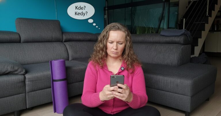 Žena sedí na zemi s mobilom a hľadá informácie o joge, no nevie kde a kedy sa cvičí