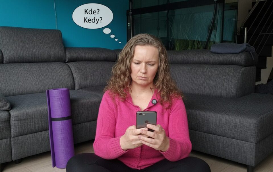 Žena sedí na zemi s mobilom a hľadá informácie o joge, no nevie kde a kedy sa cvičí